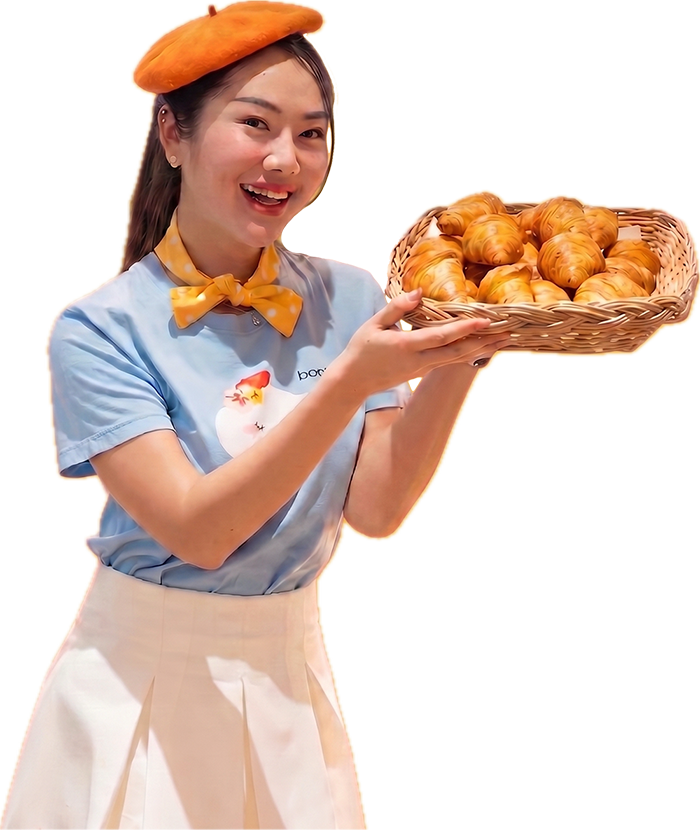 A smiling Bonjour team member holding a basket of fresh croissants